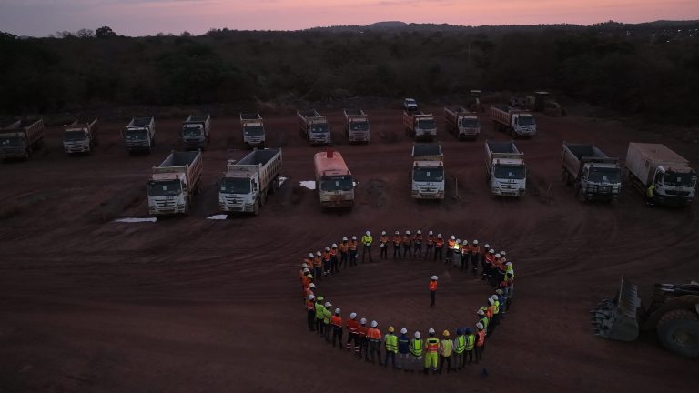 Flotte de camions alignés et équipes réunies sur un site à l'aube