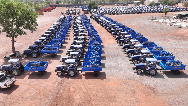 Parc de tracteurs du groupe près de Bobo-Dioulasso : tracteurs bleus attelés à leurs remorques, vue aérienne de janvier 2026